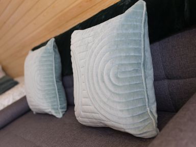 Two light blue pillows on a dark gray sofa with a wooden wall in the background at Green Fields in St Buryan