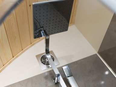 A modern showerhead with a square design and a wooden wall at Green Fields in St Buryan