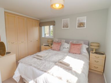 A bedroom with a double bed two bedside tables lamps and a wardrobe at Robellen Corner in Adderbury