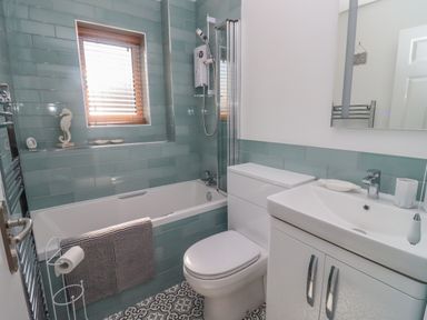 A bathroom with a bathtub shower toilet sink and window at Robellen Corner in Adderbury