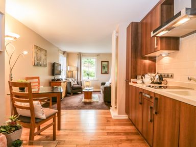 An open plan living room and kitchen with wooden cabinets and flooring at Cosy Corner in the Lakes in Greystoke
