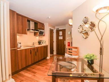 A kitchen area with wooden cabinets a glass table with a chair and decorative mirrors on the wall at Cosy Corner in the Lakes in Greystoke