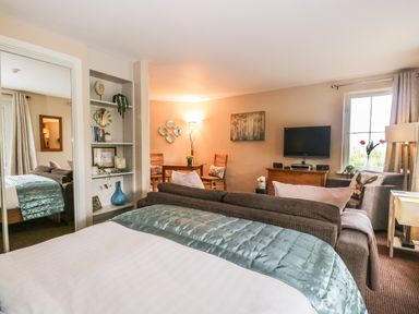 A room with a bed a sofa a television and a dining table at Cosy Corner in the Lakes Greystoke