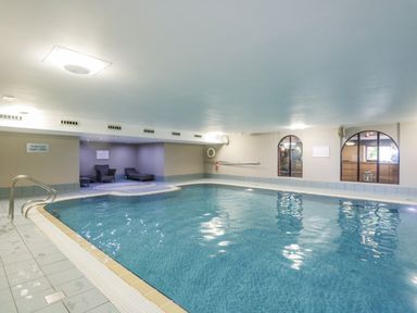 An indoor swimming pool with three lounge chairs in a corner at Cosy Corner in the Lakes Greystoke