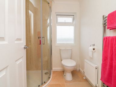 A bathroom with a corner shower, toilet, window with blinds, and pink towels at Ridge's Retreat No 7 Kigbeare Lodges in Ashbury Resort near Fowley Cross Sourton Down and Okehampton
