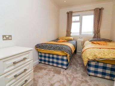 A bedroom with two single beds a chest of drawers and a window with curtains at Ridge's Retreat No 7 Kigbeare Lodges Ashbury Resort near Fowley Cross Sourton Down and Okehampton