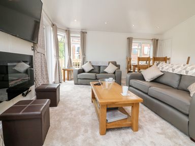 A living room with two leather sofas a wooden coffee table and a wall-mounted television at Ridge's Retreat No 7 Kigbeare Lodges Ashbury Resort near Fowley Cross Sourton Down and Okehampton