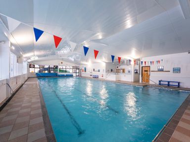 An indoor swimming pool with red white and blue bunting and tiled floor at Ridge's Retreat No 7 Kigbeare Lodges Ashbury Resort near Fowley Cross Sourton Down and Okehampton