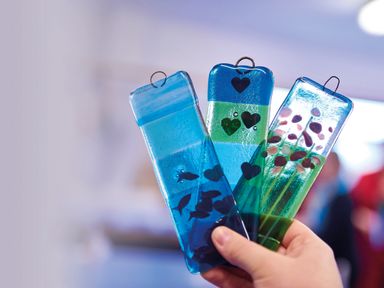 A hand holding three rectangular glass ornaments with fish, hearts, and flower designs at Ridges Retreat No 7 Kigbeare Lodges Ashbury Resort near Fowley Cross Sourton Down and Okehampton