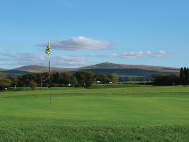 A golf course with a flag on the green and hills in the background at Ridge's Retreat No 7 Kigbeare Lodges Ashbury Resort near Fowley Cross Sourton Down and Okehampton