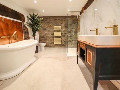 A bathroom with a bathtub toilet shower and double sink at Plas Glan Yr Afon in Llangernyw