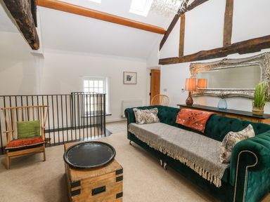 A living room with a green sofa a wooden chair a wooden chest and a large ornate mirror at Plas Glan Yr Afon in Llangernyw