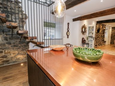 A kitchen area with a copper countertop island featuring bowls and a staircase with wooden steps and metal railings at Plas Glan Yr Afon in Llangernyw