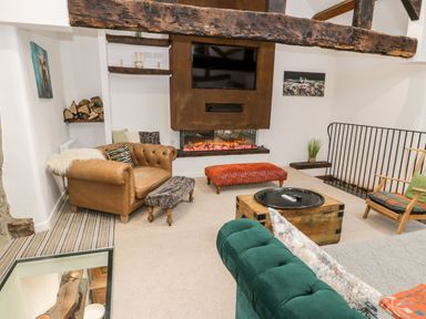 A living room with a fireplace a television a leather chair and wooden furniture at Plas Glan Yr Afon in Llangernyw