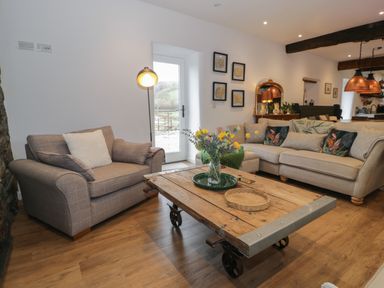 A living room with two sofas a wooden coffee table with flowers on it and wall art at Plas Glan Yr Afon in Llangernyw