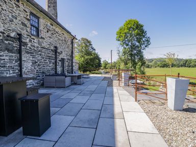 An outdoor area with stone wall and patio furniture at Plas Glan Yr Afon in Llangernyw