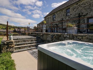 A hot tub beside stone steps at Plas Glan Yr Afon in Llangernyw