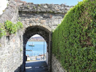 A stone archway leading to water and boats at Plas Glan Yr Afon Llangernyw