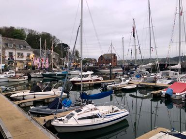 A harbor with boats docked along the pier and buildings in the background at Trelowen in St Issey near Padstow