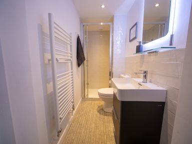 A bathroom with a shower enclosure toilet sink cabinet and heated towel rail at Trelowen in St Issey near Padstow
