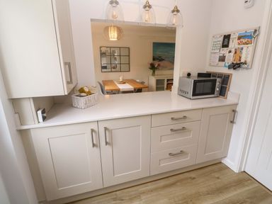 A kitchen with cabinets and a microwave at Trelowen in St Issey near Padstow