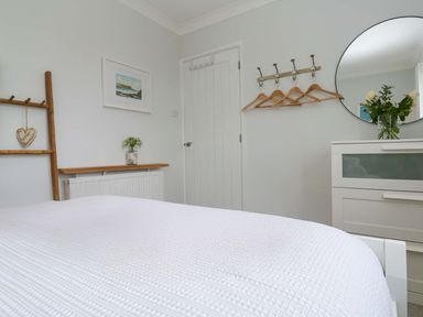 A bedroom with a bed, mirror, and coat hooks at Trelowen St Issey near Padstow