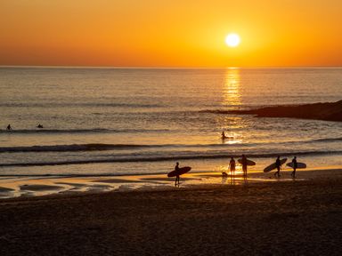 A sunset with surfers on a beach at Trelowen St Issey near Padstow