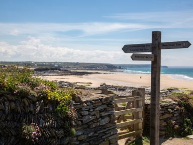 A beach scene with a signpost showing directions at Trelowen St Issey near Padstow