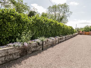A gravel driveway with raised flower beds and a tall hedge at Little Lugg in Cross Keys near Hereford