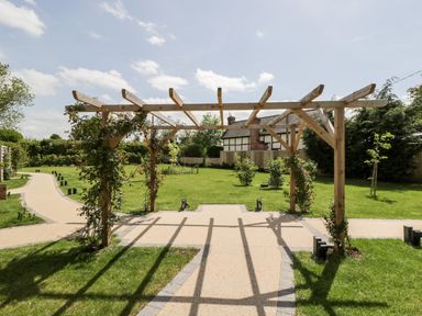 A garden with pathways and a wooden pergola with climbing plants at Little Lugg in Cross Keys near Hereford