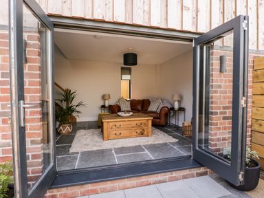 A living room with a brown leather sofa a wooden coffee table and a plant at Little Lugg in Cross Keys near Hereford