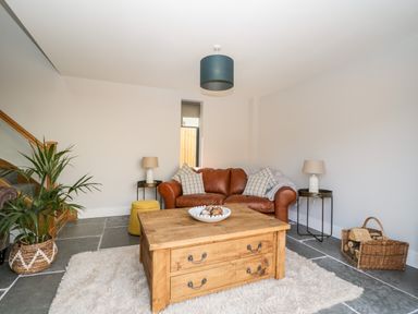 A living room with a brown leather sofa two side tables with lamps a wooden coffee table and a plant at Little Lugg in Cross Keys near Hereford