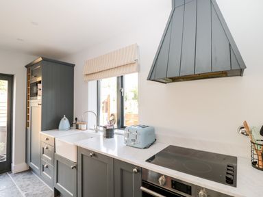 A kitchen with grey cabinets a white countertop a blue toaster and kettle near a window at Little Lugg in Cross Keys near Hereford