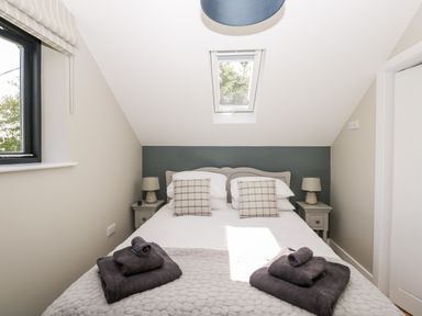 A bedroom with a double bed two bedside tables with lamps a window and a skylight at Little Lugg in Cross Keys near Hereford