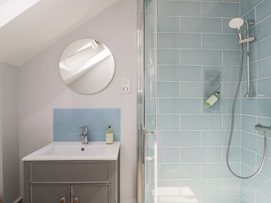 A bathroom with a sink cabinet mirror and a shower with blue tiles at Little Lugg in Cross Keys near Hereford