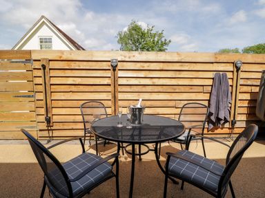 A patio area with a round black metal table and four chairs with cushions at Little Lugg in Cross Keys near Hereford