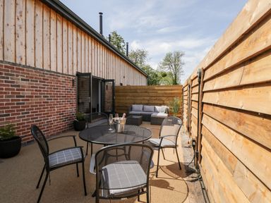 An outdoor patio area with a round metal table and four chairs a sofa set and wooden fencing at Little Lugg in Cross Keys near Hereford