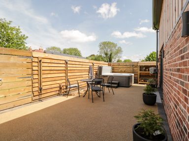 A fenced outdoor patio area with table and chairs and a hot tub at Little Lugg in Cross Keys near Hereford