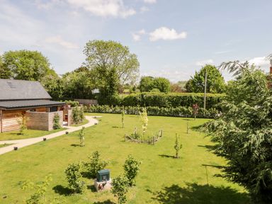 A garden with a wooden building pathway small trees and green grass at Little Lugg in Cross Keys near Hereford