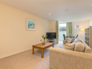 A living room with a sofa coffee table television and dining table at Golden Sands in Carbis Bay