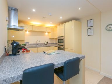 A kitchen with yellow cabinets a gray countertop an oven and a sink at Golden Sands in Carbis Bay