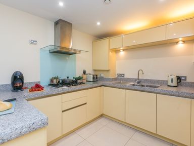 A kitchen with a gas stove, sink, toaster, kettle, and coffee machine at Golden Sands in Carbis Bay