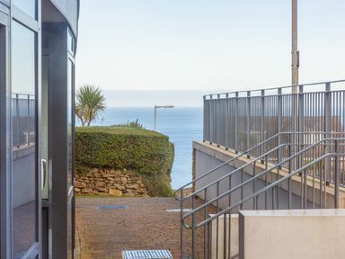 View of a pathway with metal railings and a bush overlooking the sea at Golden Sands in Carbis Bay