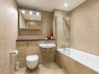 A small bathroom with a wall-mounted toilet sink bathtub and shower at Golden Sands in Carbis Bay