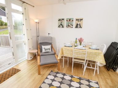 A dining area with a table set for four and a lounge chair with a footrest at Seas The Day in Ventnor