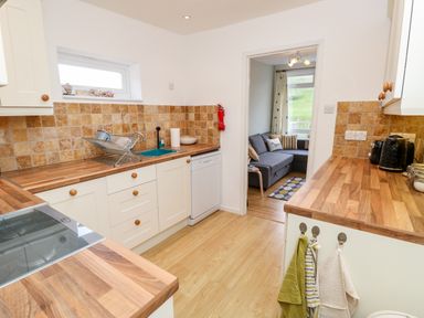 A kitchen with wooden countertops a sink a dish rack and a view into a living room at Seas The Day in Ventnor