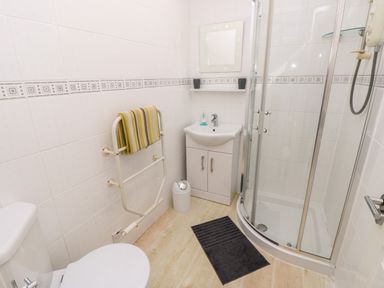 A bathroom with a toilet a towel rack with a towel a sink with a mirror and a glass shower enclosure at Seas The Day in Ventnor