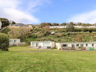 Row of single-story houses with small fenced decks on a grassy area at Seas The Day in Ventnor