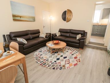 A living room with two brown sofas and a round patterned rug at Stone's Throw in Amble