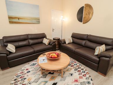 A living room with two leather sofas a round wooden coffee table and a patterned rug at Stone's Throw in Amble